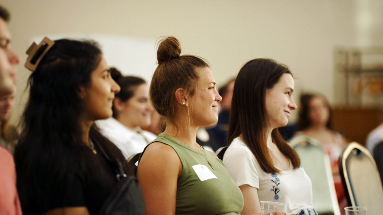 Image from Theology on Tap event with a focus on three women sitting and listening to the events speakers